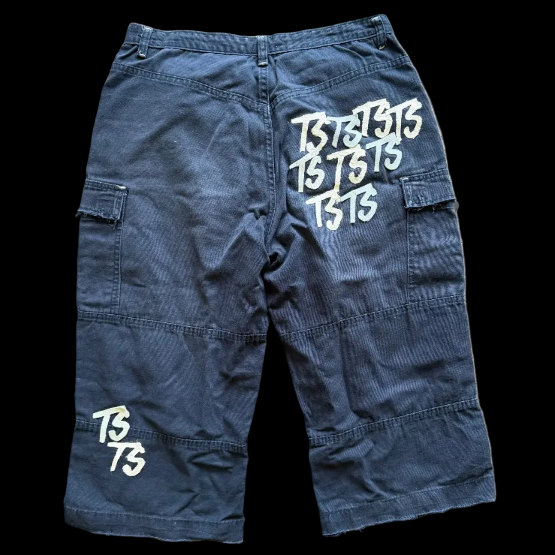 Blue cargo pants with 'TSTTS' branding on a wooden floor